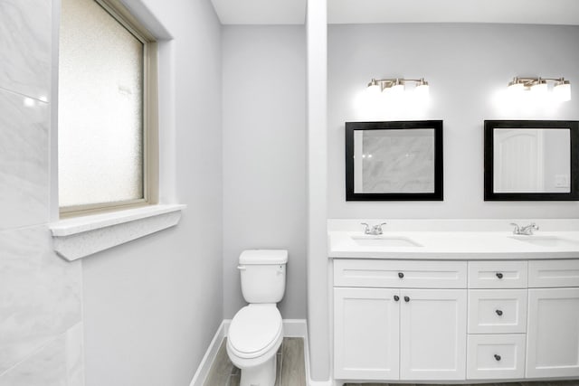 bathroom with plenty of natural light, wood-type flooring, toilet, and vanity