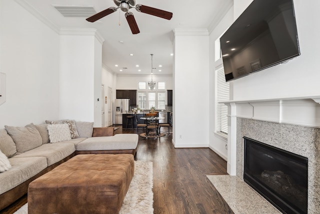 living room with a fireplace, dark hardwood / wood-style floors, ceiling fan, and ornamental molding