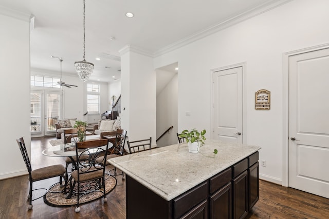 kitchen with a kitchen island, dark brown cabinetry, ornamental molding, pendant lighting, and dark wood-type flooring