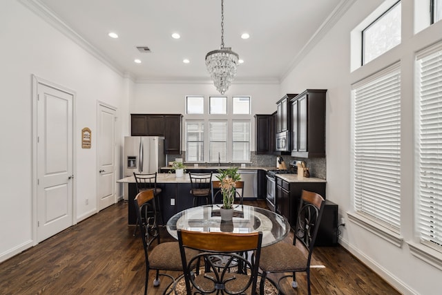 kitchen with dark wood-type flooring, hanging light fixtures, appliances with stainless steel finishes, and a kitchen island