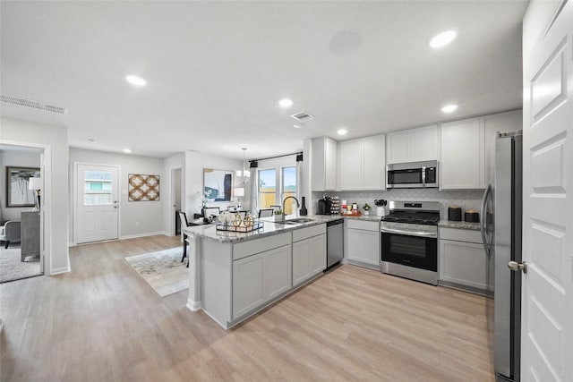 kitchen with sink, stainless steel appliances, light hardwood / wood-style flooring, and kitchen peninsula