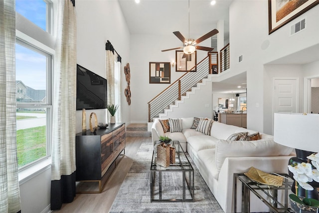 living room with a towering ceiling, a wealth of natural light, and wood-type flooring