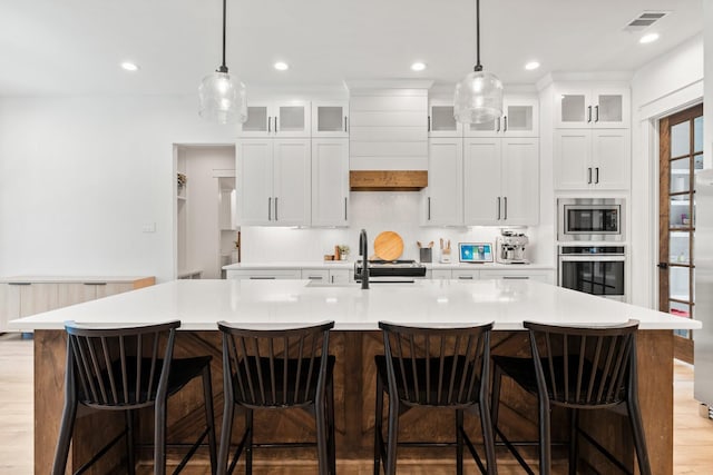 kitchen featuring a spacious island, white cabinetry, stainless steel appliances, sink, and a breakfast bar