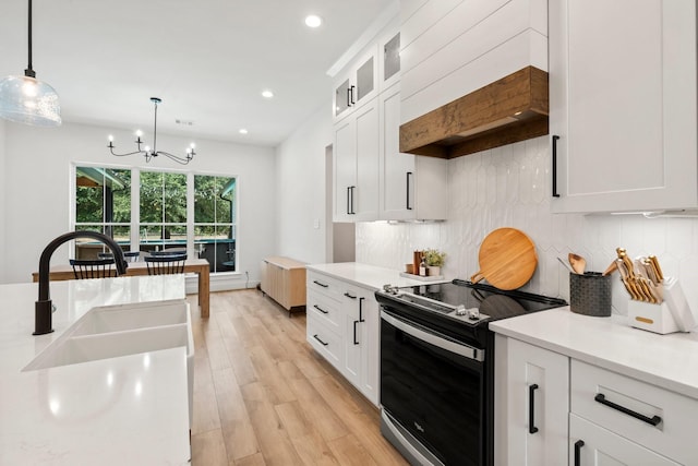 kitchen featuring white cabinetry, decorative light fixtures, electric range, and light wood-type flooring