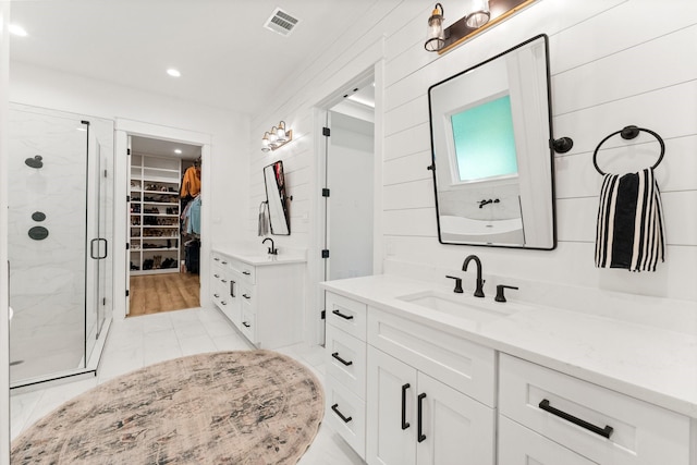 bathroom featuring a shower with shower door and vanity