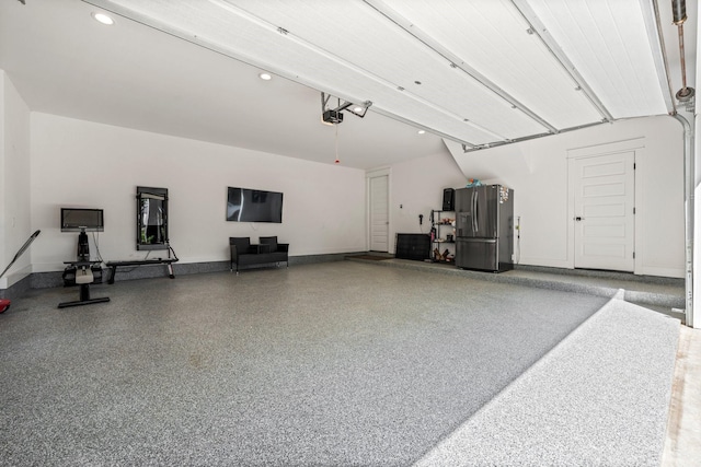 garage with a garage door opener and stainless steel fridge