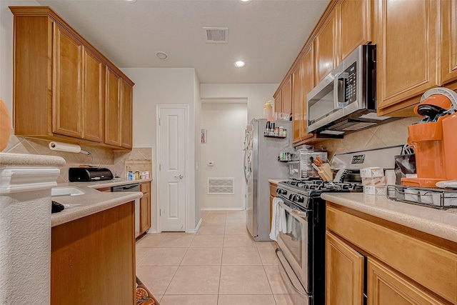 kitchen featuring light tile patterned flooring, decorative backsplash, and appliances with stainless steel finishes