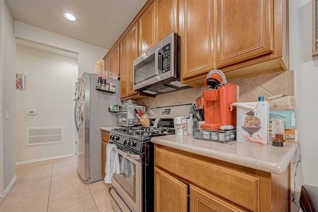 kitchen with decorative backsplash, light tile patterned floors, and appliances with stainless steel finishes