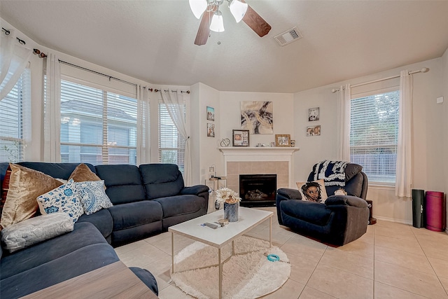 living room with a tile fireplace, light tile patterned floors, and ceiling fan