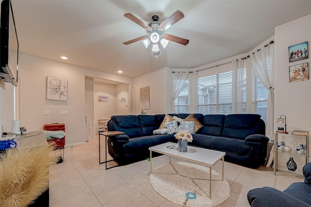 living room featuring ceiling fan, light tile patterned floors, and a textured ceiling