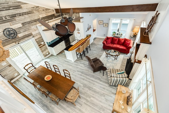 living room with ceiling fan, beam ceiling, and light wood-type flooring