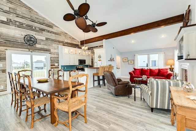 dining area featuring high vaulted ceiling, light hardwood / wood-style flooring, wooden walls, beamed ceiling, and ceiling fan