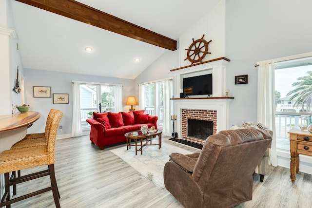 living room with beamed ceiling, a brick fireplace, high vaulted ceiling, and light wood-type flooring