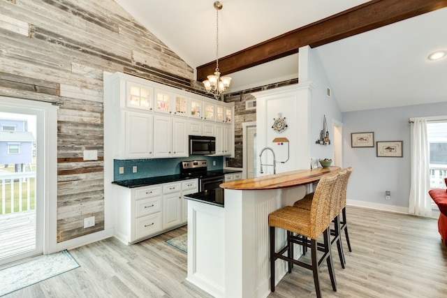 kitchen with appliances with stainless steel finishes, backsplash, lofted ceiling with beams, white cabinets, and kitchen peninsula