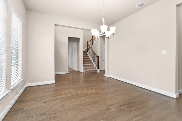 unfurnished room with plenty of natural light, a chandelier, and dark hardwood / wood-style flooring