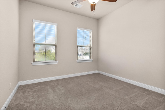 carpeted empty room with ceiling fan and a wealth of natural light