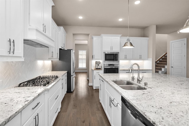 kitchen with hanging light fixtures, sink, white cabinets, stainless steel appliances, and light stone counters