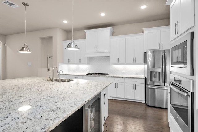 kitchen featuring sink, hanging light fixtures, appliances with stainless steel finishes, and white cabinets