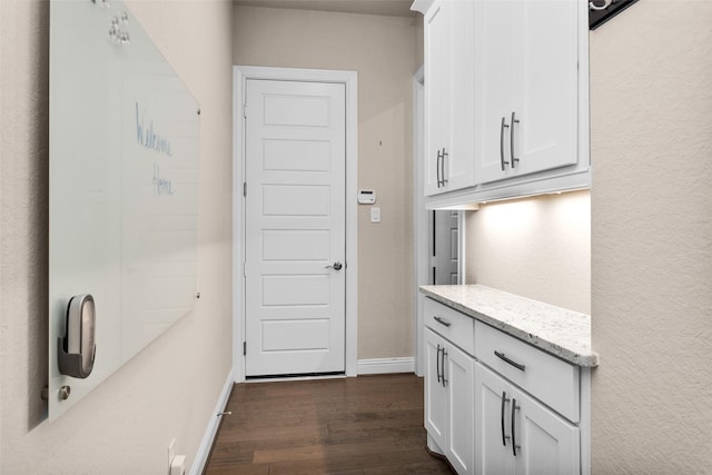 kitchen with white cabinets, light stone counters, and dark hardwood / wood-style flooring