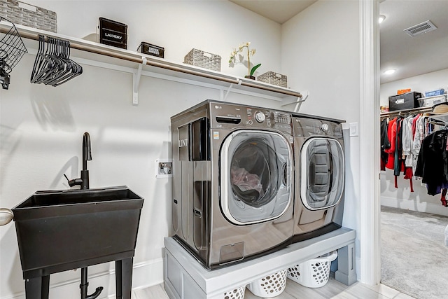 laundry room featuring sink, washer and dryer, and light carpet