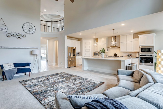 living room featuring light carpet, ceiling fan, and a high ceiling