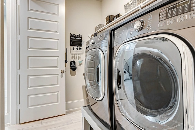 clothes washing area featuring separate washer and dryer and light hardwood / wood-style flooring