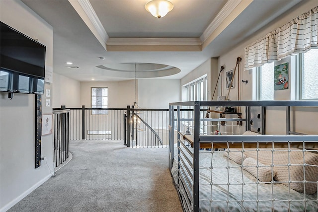 hallway featuring a tray ceiling, carpet floors, and ornamental molding