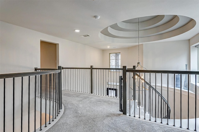 corridor featuring carpet flooring and a tray ceiling