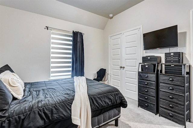 bedroom featuring lofted ceiling, light colored carpet, and a closet