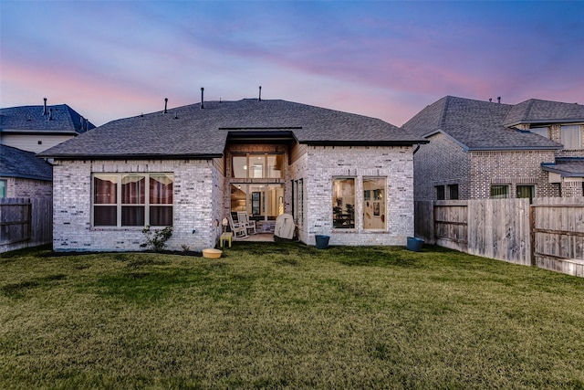 back house at dusk with a yard and a patio