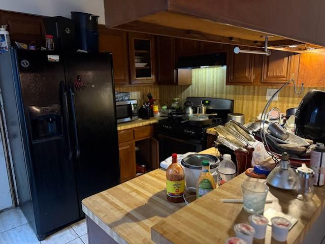 kitchen featuring black appliances, ventilation hood, and light tile patterned flooring