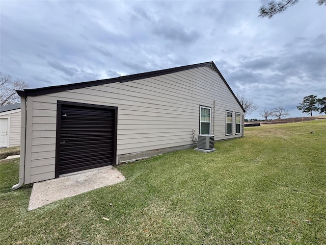 view of outbuilding featuring a garage, a yard, and central AC unit