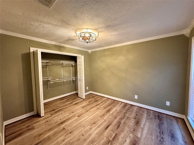 unfurnished bedroom featuring crown molding, a closet, wood finished floors, and a textured ceiling