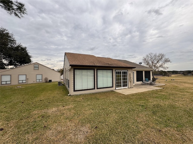 rear view of property with roof with shingles, central air condition unit, a yard, and a patio area
