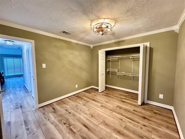 unfurnished bedroom with a textured ceiling, a closet, ornamental molding, and light wood-type flooring