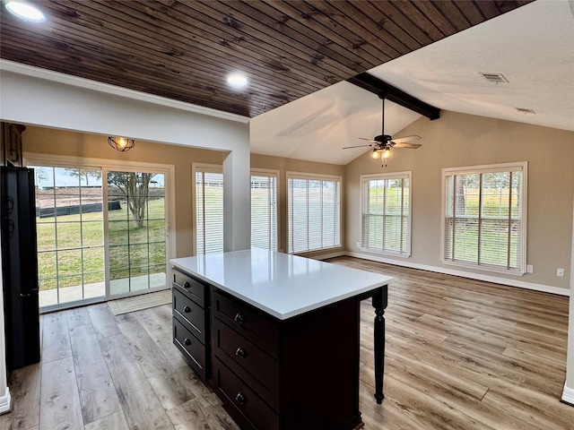 kitchen featuring a kitchen breakfast bar, a kitchen island, vaulted ceiling with beams, light hardwood / wood-style flooring, and ceiling fan