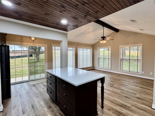 kitchen with light wood finished floors, a kitchen bar, ceiling fan, visible vents, and dark cabinets