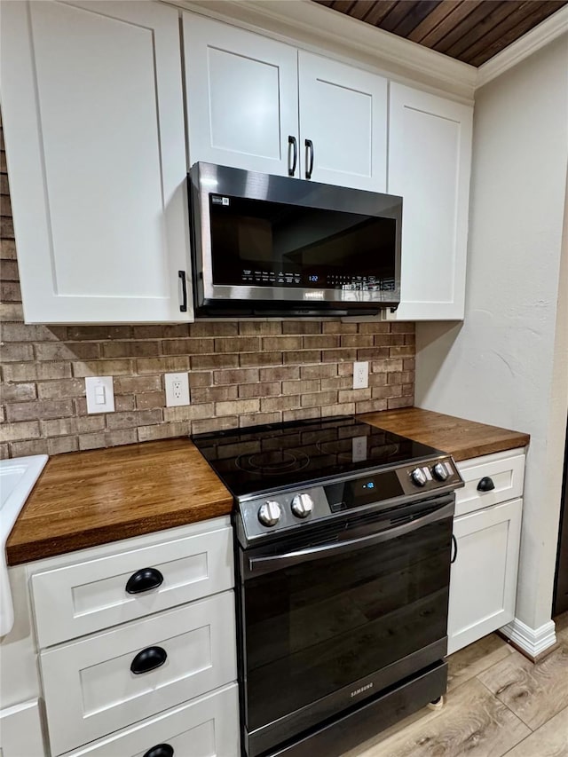 kitchen with wooden counters, stainless steel appliances, ornamental molding, and decorative backsplash