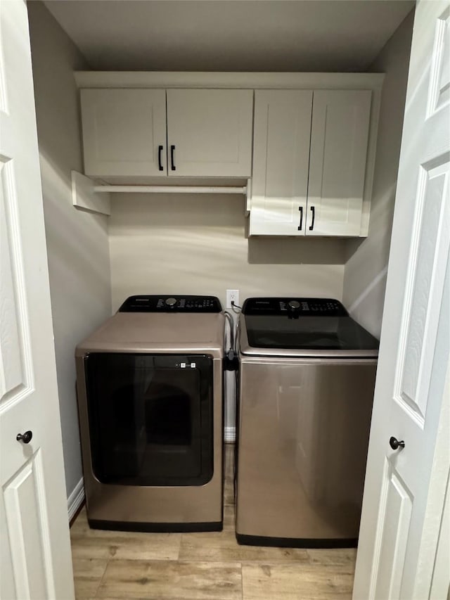 washroom with cabinets, washer and dryer, and light hardwood / wood-style floors