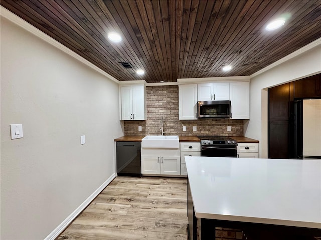 kitchen featuring white cabinetry, decorative backsplash, a sink, black appliances, and ornamental molding