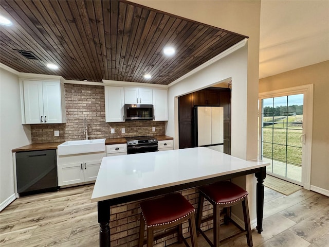 kitchen featuring stainless steel microwave, a sink, range with electric cooktop, a breakfast bar, and dishwasher