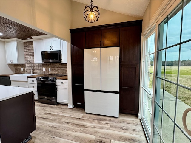 kitchen with stainless steel microwave, a sink, black electric range oven, freestanding refrigerator, and lofted ceiling