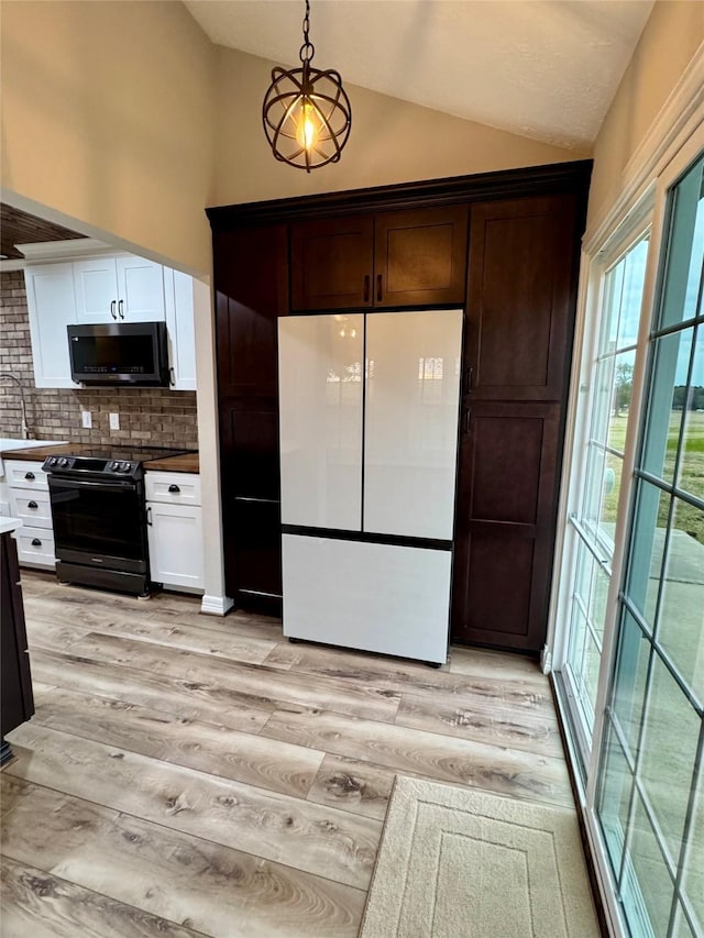 kitchen with white refrigerator, light hardwood / wood-style floors, backsplash, vaulted ceiling, and electric range