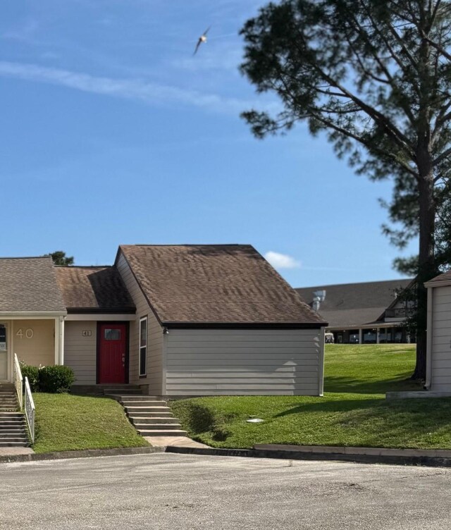 view of front of home with a front lawn and roof with shingles