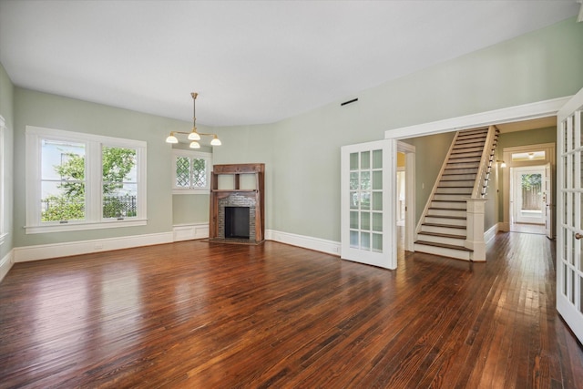 unfurnished living room featuring a brick fireplace, dark hardwood / wood-style flooring, and french doors