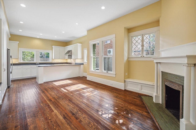 unfurnished living room featuring sink, dark hardwood / wood-style floors, and a wealth of natural light