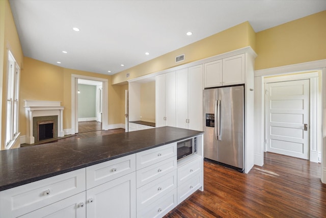 kitchen featuring dark wood-type flooring, white cabinetry, stainless steel appliances, and dark stone counters