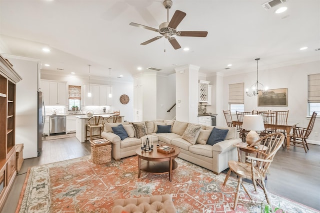 living room featuring crown molding, hardwood / wood-style floors, and ceiling fan with notable chandelier