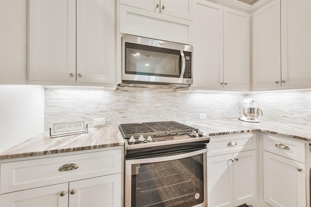 kitchen with stainless steel appliances, white cabinetry, light stone countertops, and decorative backsplash