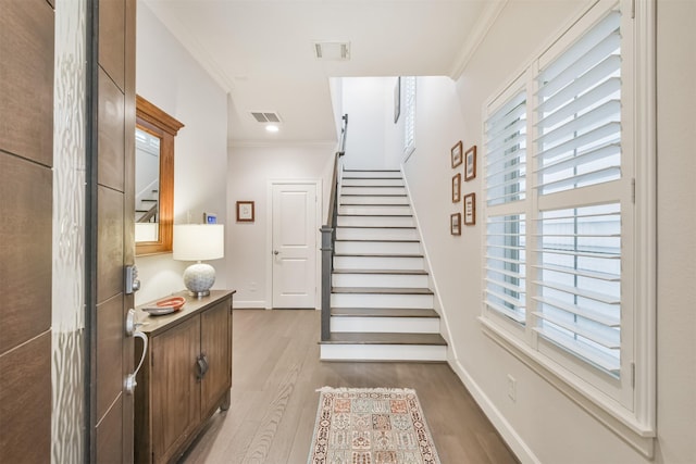 foyer with hardwood / wood-style flooring and crown molding